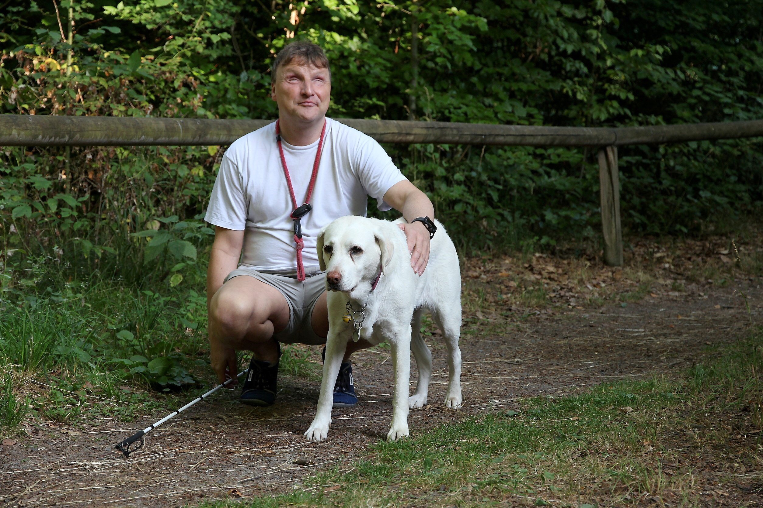 Im Wald. Per kniet neben seinem Hund Peggy. Foto von HNA-Artikel "Blinder Waldläufer, seit neun Jahren ungeküsst", Sommer 2018